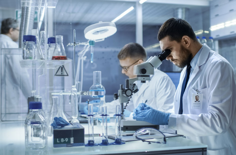 Natural Pharmaceuticals Hepactum&trade; FORTE Teadlane valges kitlis uurib mikroskoobi all proovi kaasaegses laboris keemiliste pudelite ja seadmetega.