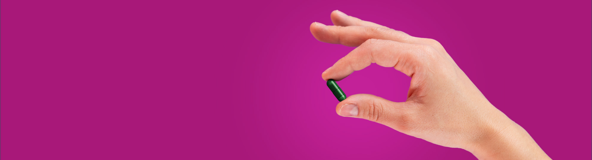 Natural Pharmaceuticals Hepactum™ FORTE Inimese käsi hoiab rohelist kapslit lilla taustal, rõhutades tervise ja ravimite teemat.