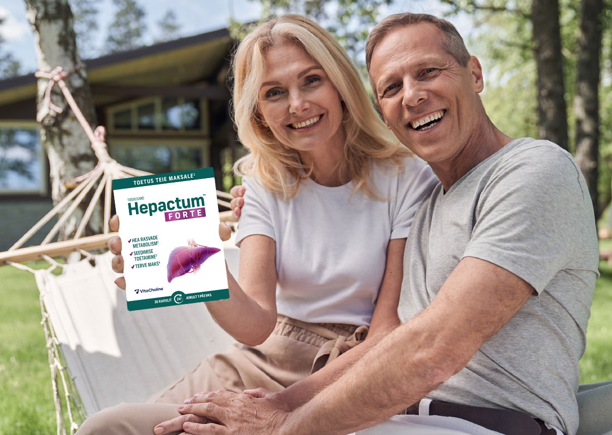 Natural Pharmaceuticals Hepactum™ FORTE Naeratav vanem paar istub koos võrkkiiges maja ja puude taustal. Naine hoiab käes toidulisandi Hepactum™ FORTE pakendit.