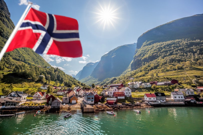 Natural Pharmaceuticals Hepactum™ FORTE Norra lipp särava päikese all fjordi ääres väikese kaluriküla taustal mägedega.